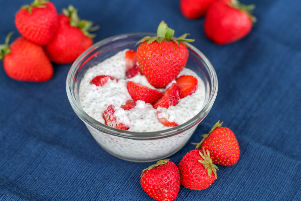 Strawberry on top of bowl of strawberry cheesecake chia seed pudding