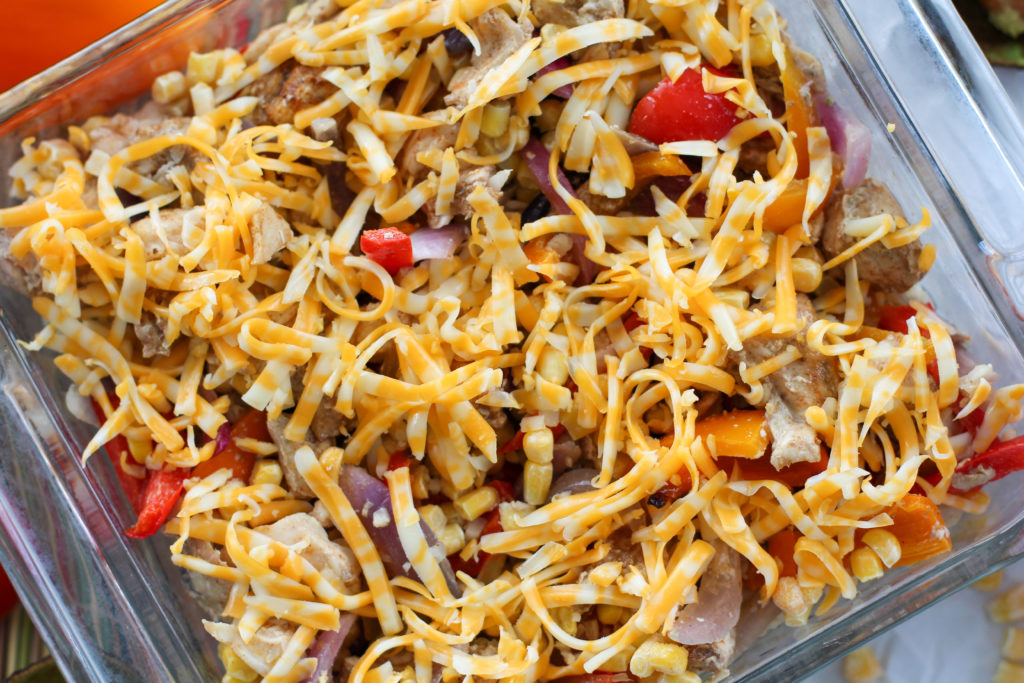 Pan of chicken fajita casserole topped with shredded cheese