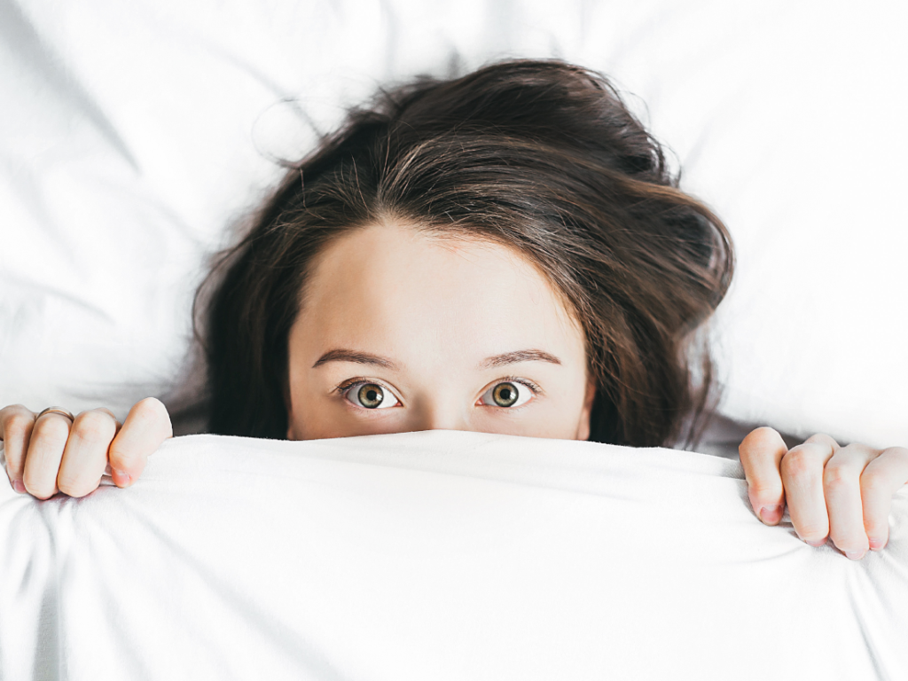 woman hiding under sheets