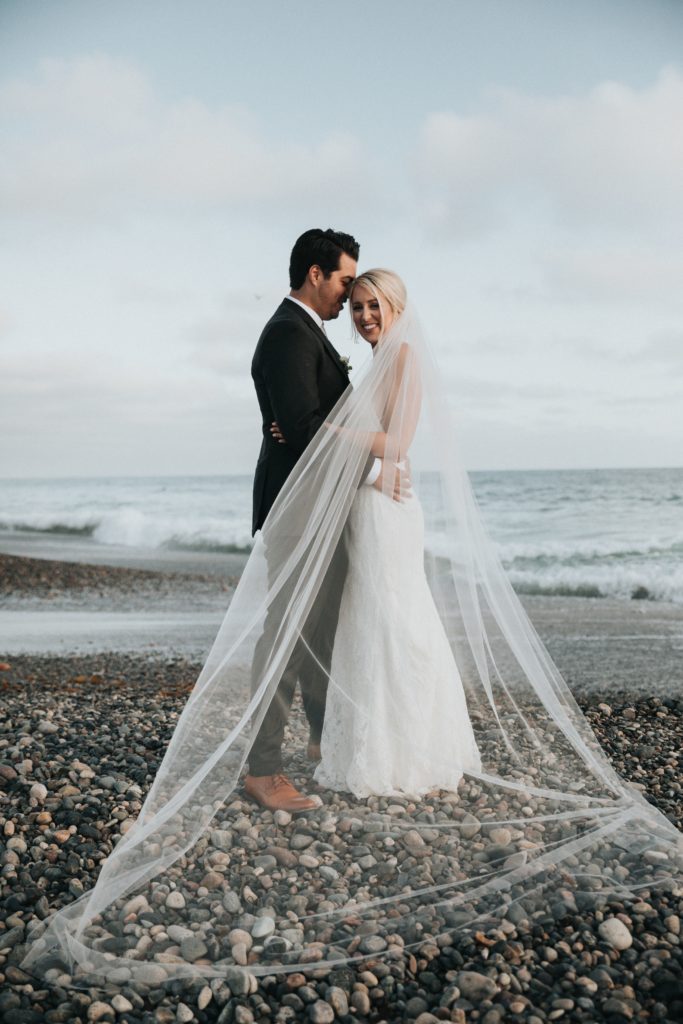 bride and groom standing on beach
