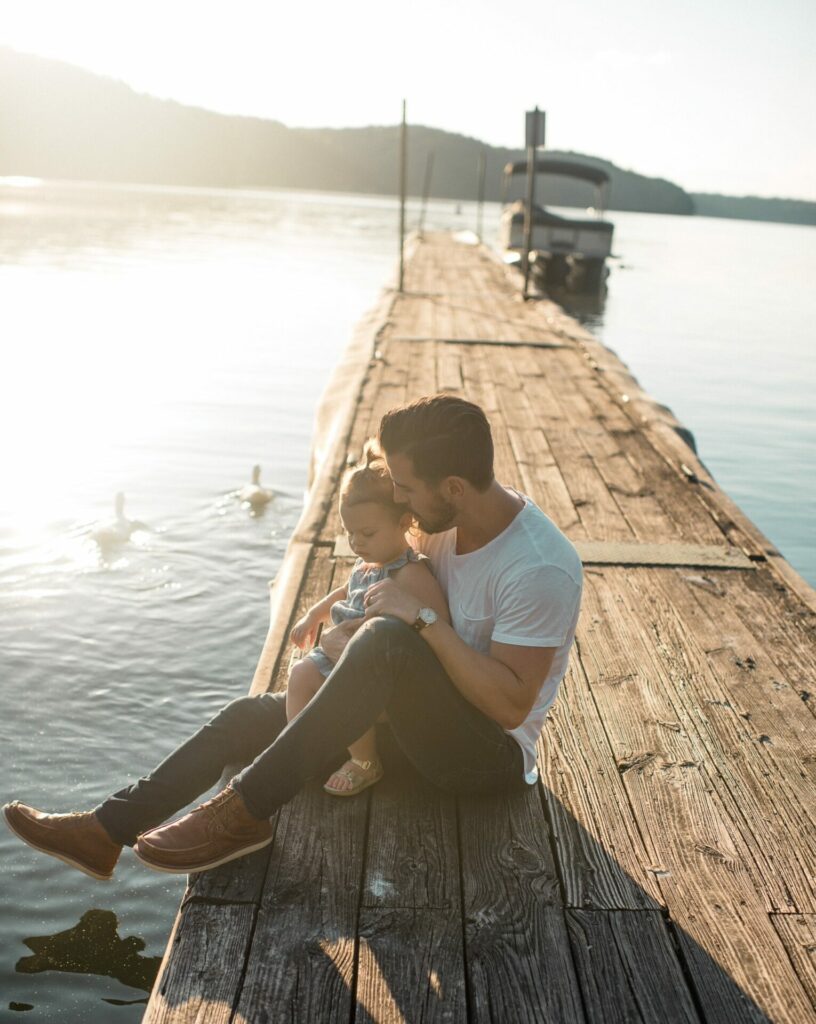 child sitting on pier with dad