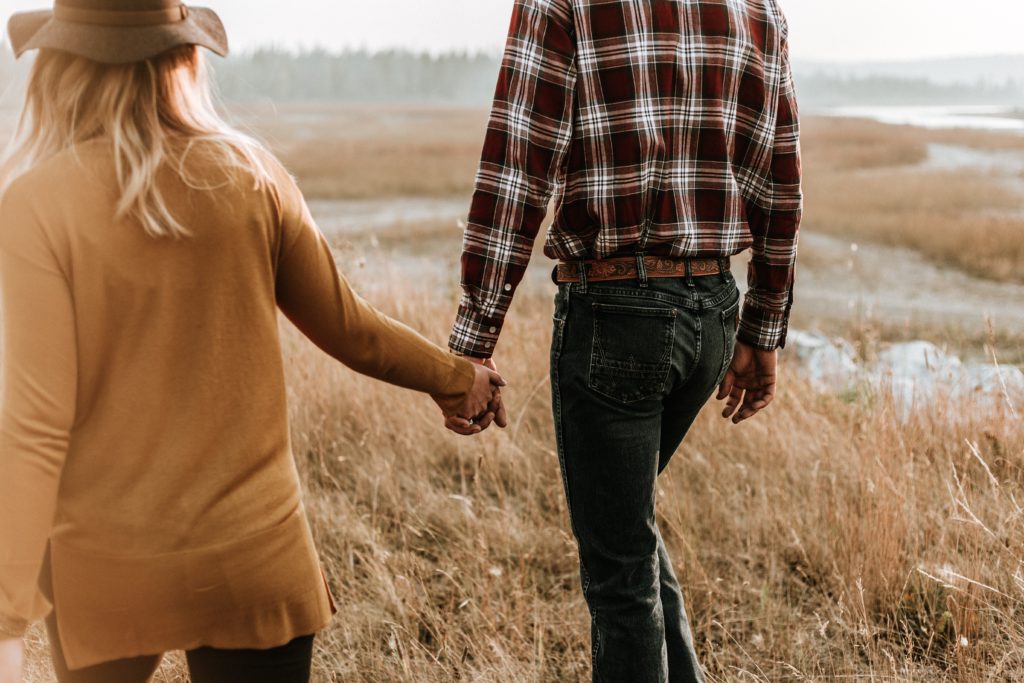 couple holding hands in field