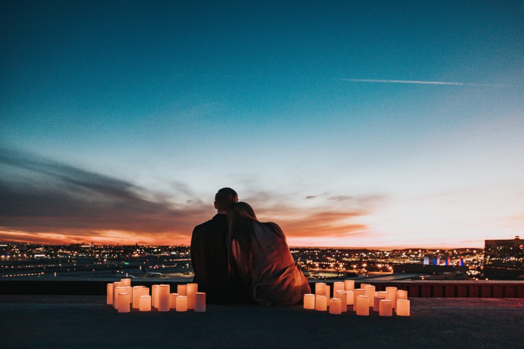 couple sitting with candles surrounding them watching sunset