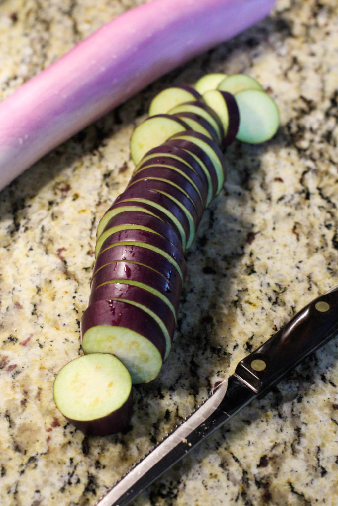 Sliced eggplant on counter with knife