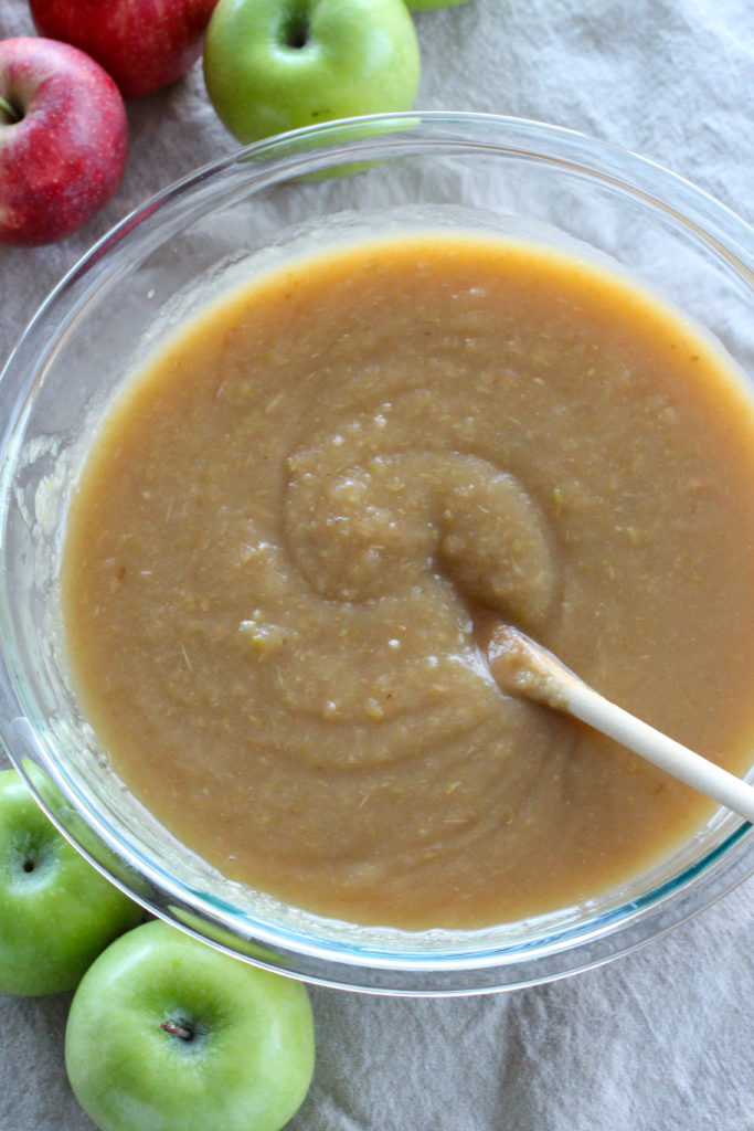 bowl of homemade applesauce surrounded by apples