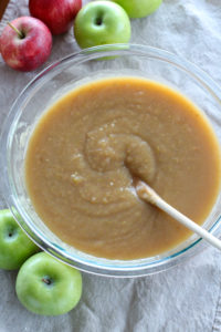 bowl of applesauce surrounded by apples