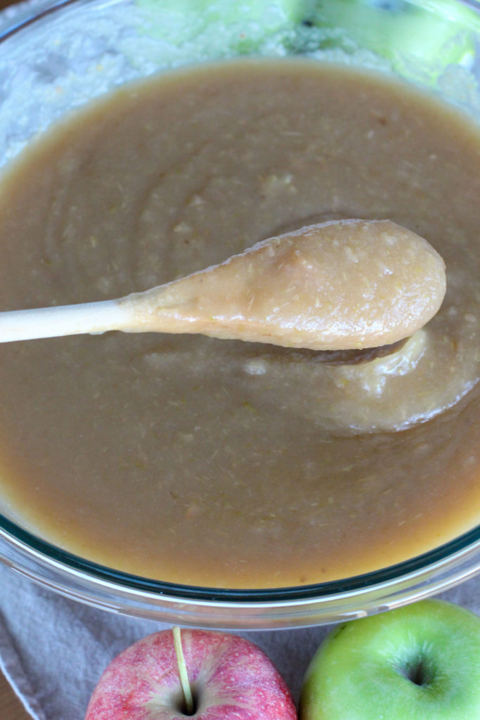 wooden spoon in large glass bowl of homemade applesauce