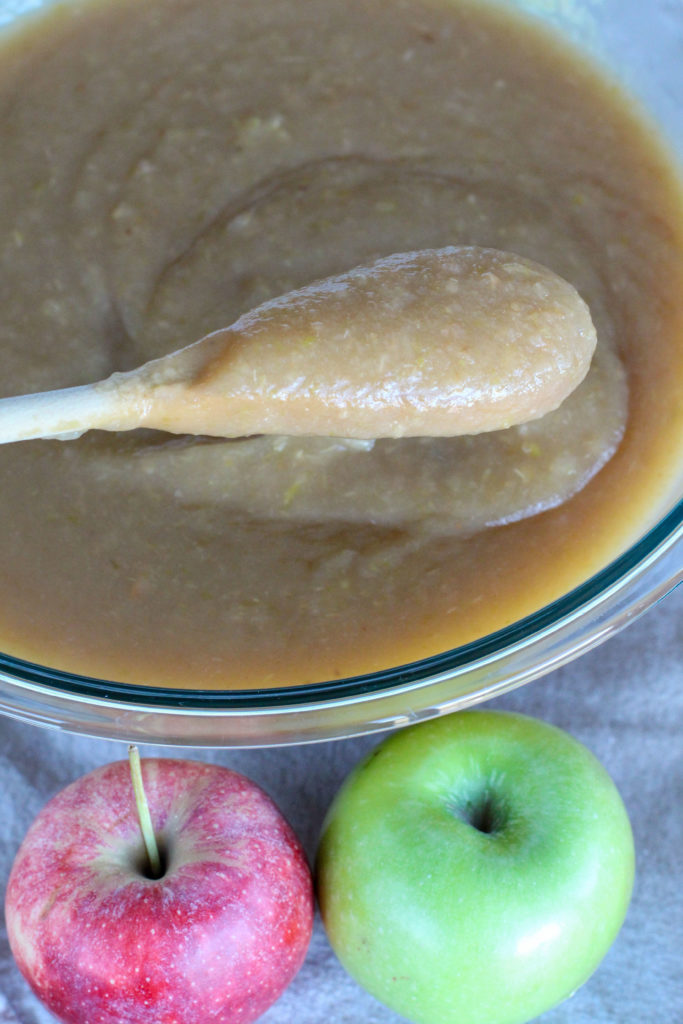 wooden spoon in large glass bowl of homemade applesauce