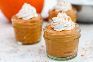 Small jars of pumpkin pie pudding topped with homemade cool whip