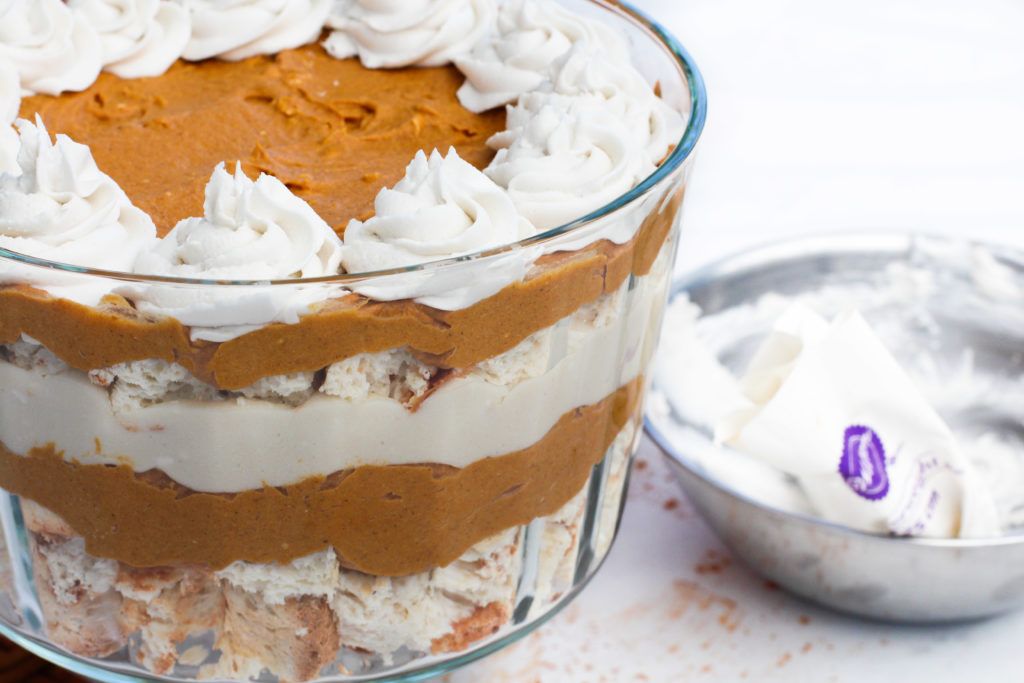 side view of pumpkin pie trifle with bowl of whipped cream next to it