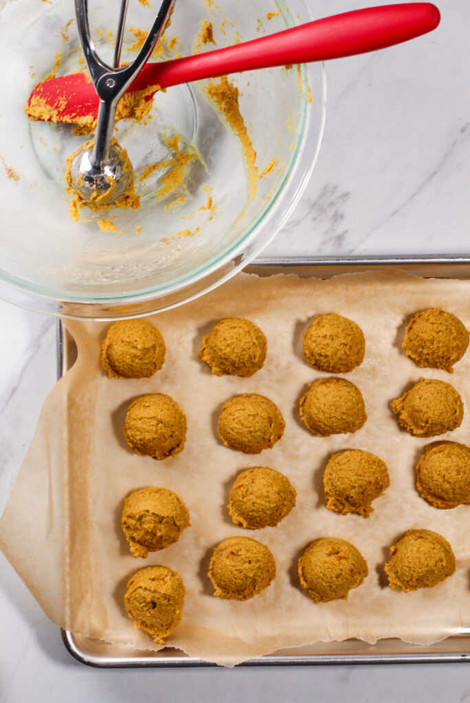 empty bowl with scatula and full cookie tray of pumpkin pie truffles