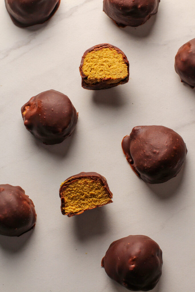 truffles laying on white counter with one cut in half revealing orange middle