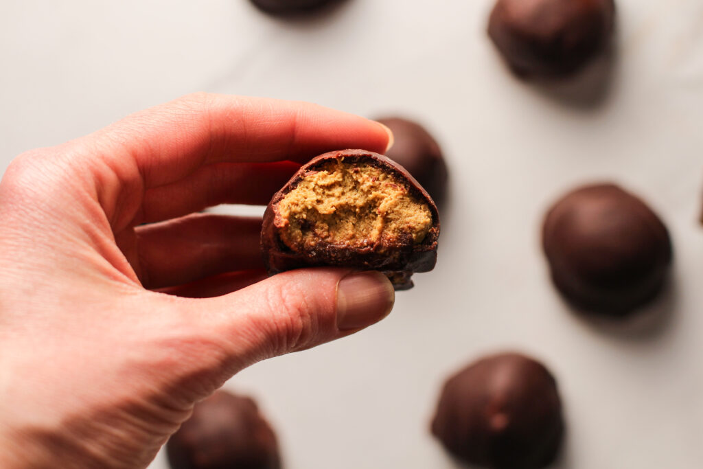 hand holding a truffle with a bite out of it