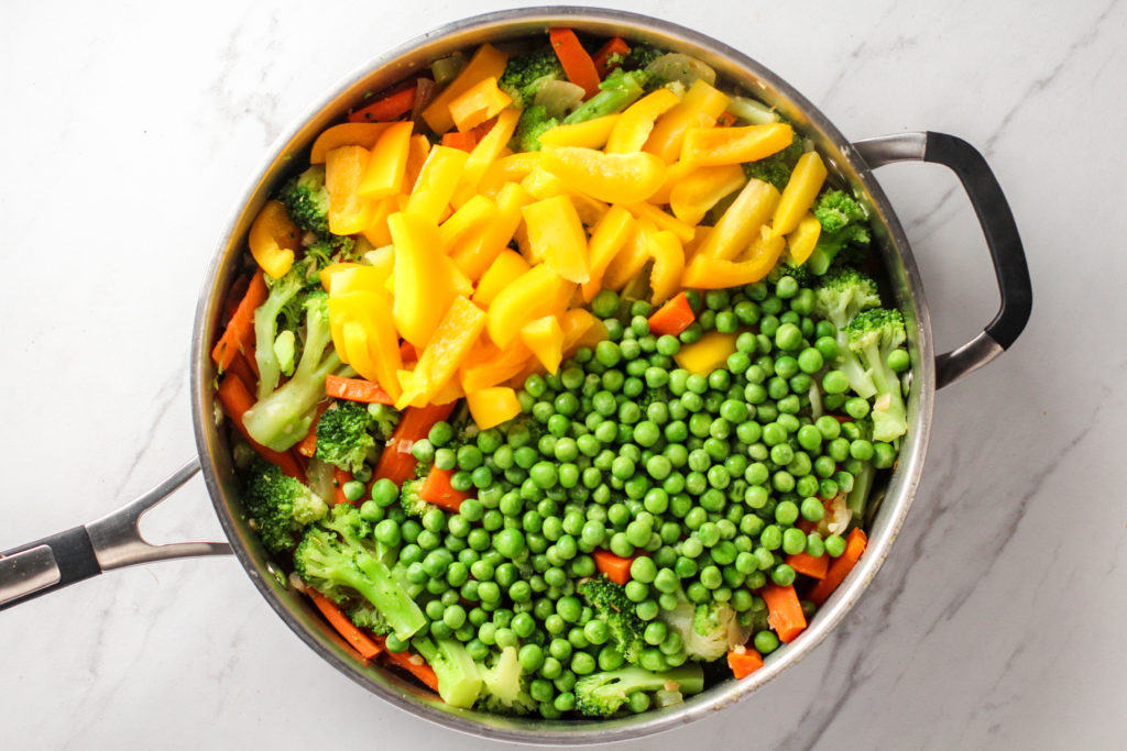 pan with bell pepper and peas on top of other stir-fry vegetables