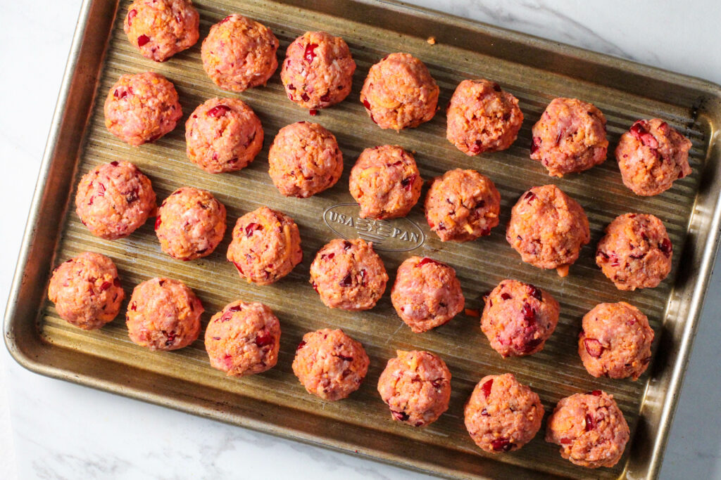 cookie sheet of raw cranberry orange meatballs