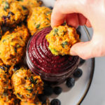 plate of blueberry meatballs with hand dipping a meatball in blueberry BBQ sauce