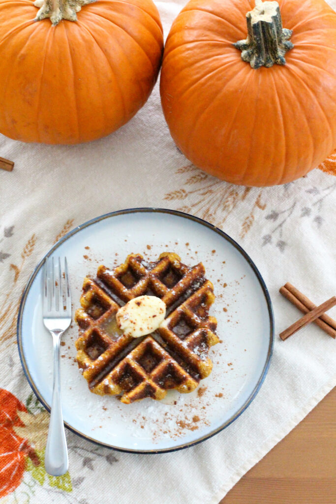 pumpkin waffle on plate with fork with pumpkins in background