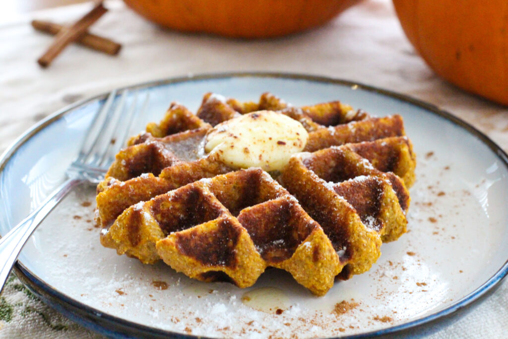 pumpkin waffle with pat of butter on topon plate with fork