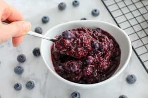hand getting a spoonful of easy berry compote