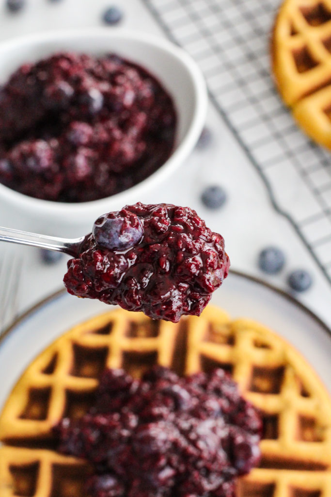 spoon holding fruit compote over waffle