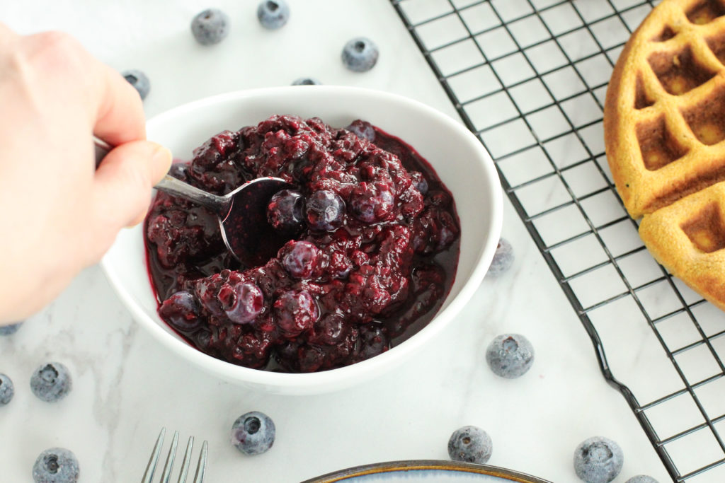 hand reaching with a spoon for easy berry compote