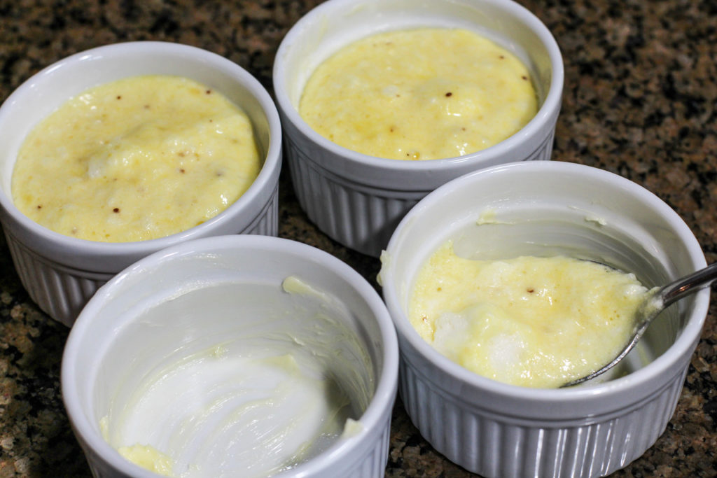 four ramekins being prepared with cheese souffle batter