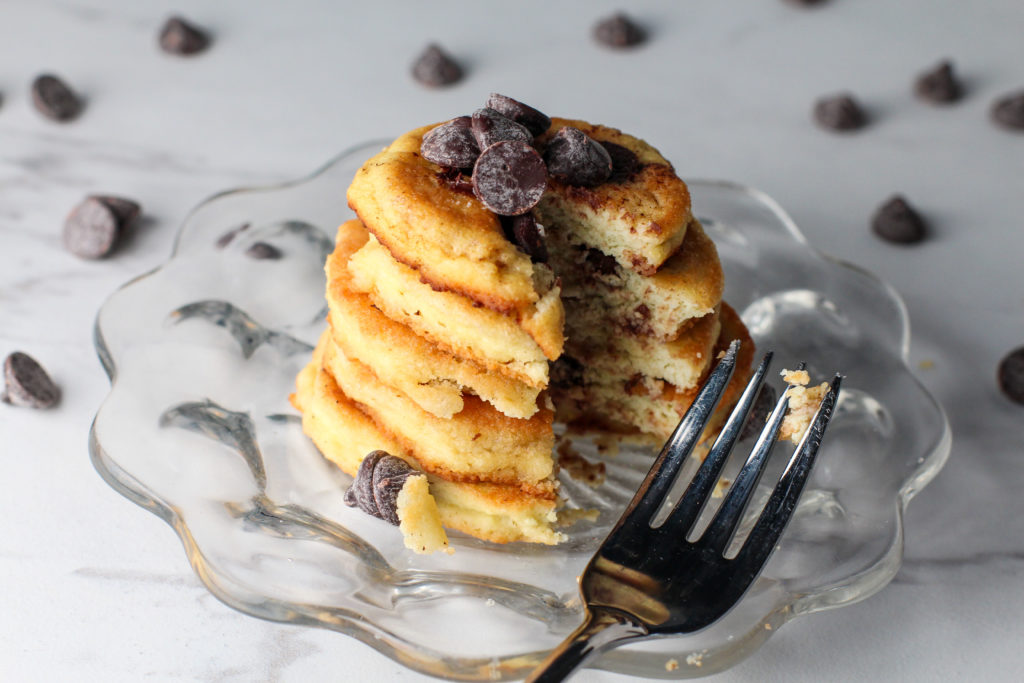 fork resting on plate of pancakes with bite missing