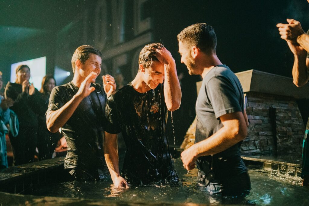 men baptizing another man with crowd clapping