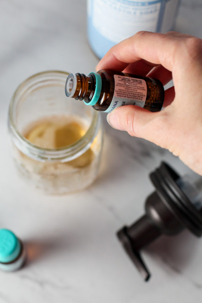 hand adding essential oils to DIY foaming hand soap