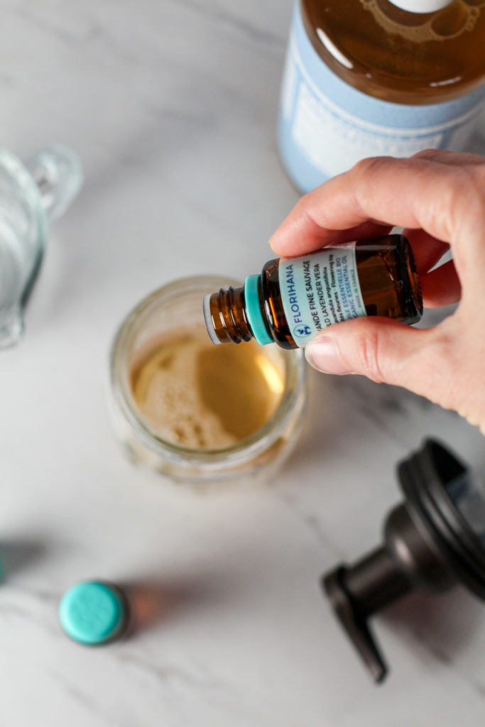 hand adding essential oils to mason jar with homemade foaming hand soap