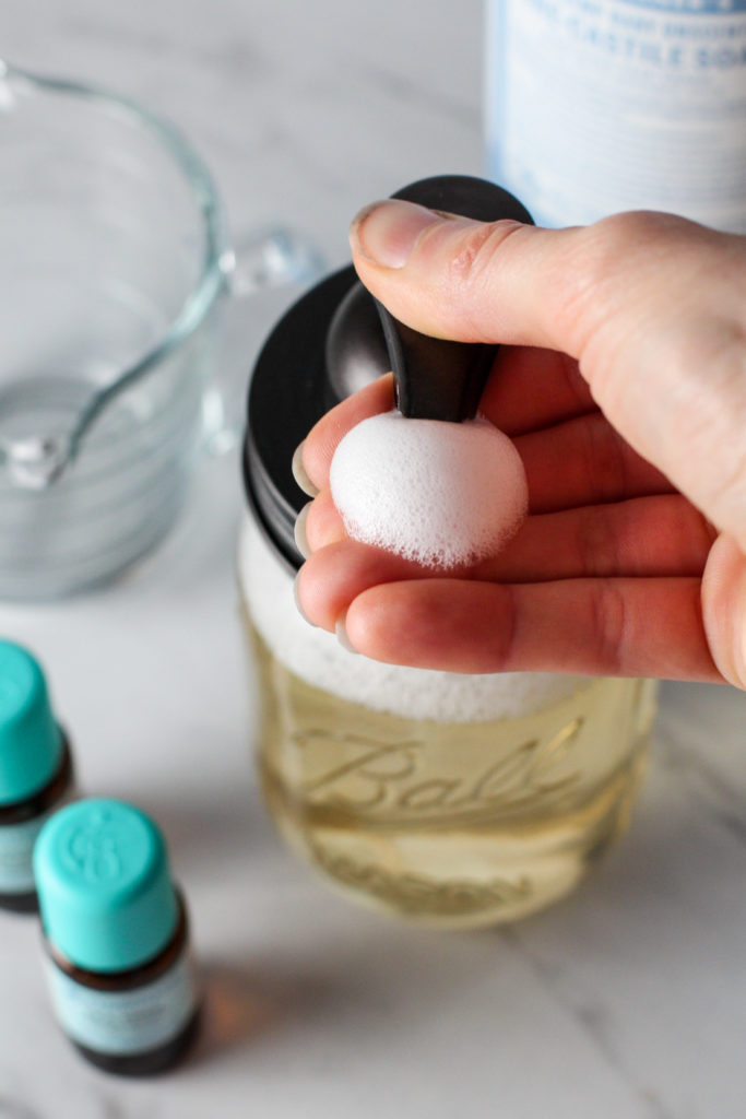 hand pressing down on foaming soap dispenser