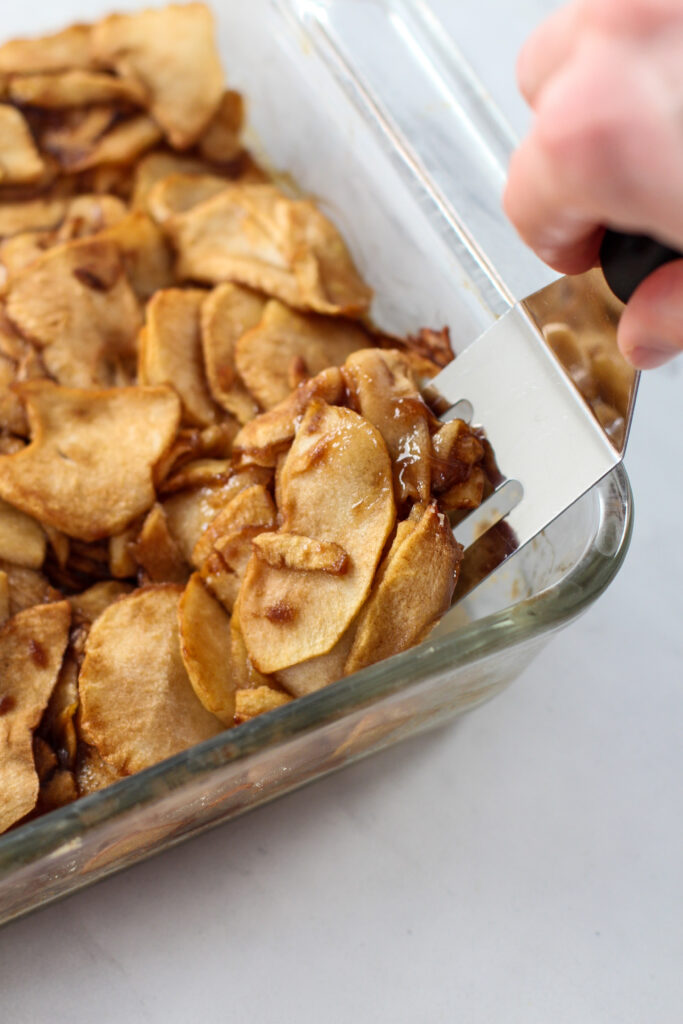 hand holding spatula serving a piece of apple pie bars