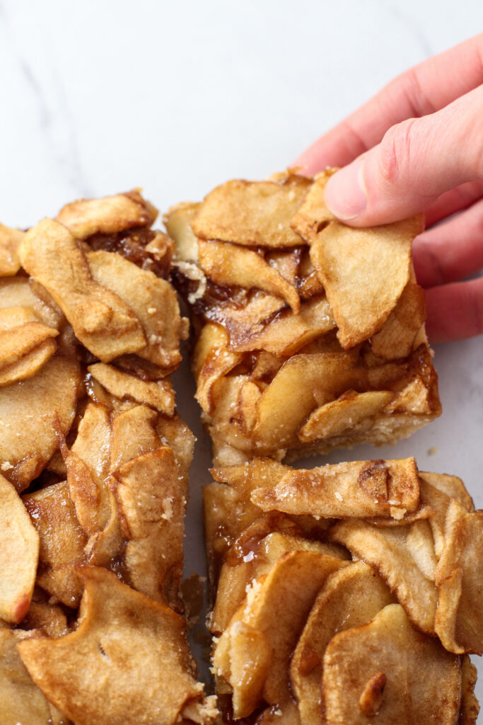 hand grabbing a corner piece of apple pie bars