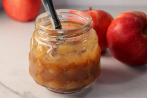Apple butter in glass jar with knife sticking out the top