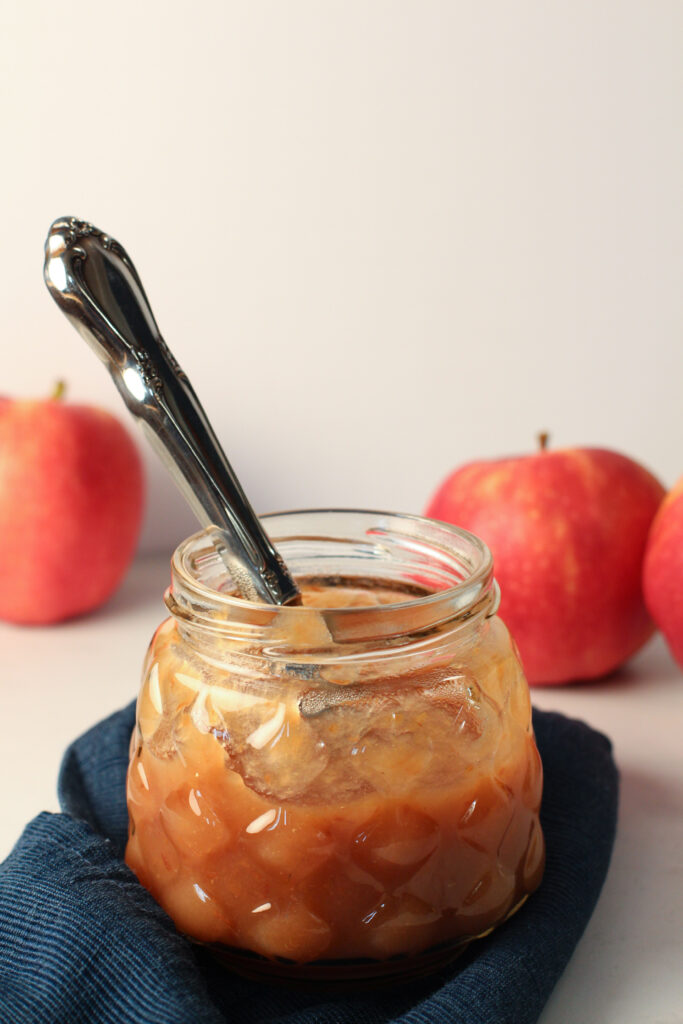 jar of apple butter with knife out the top and apples in background