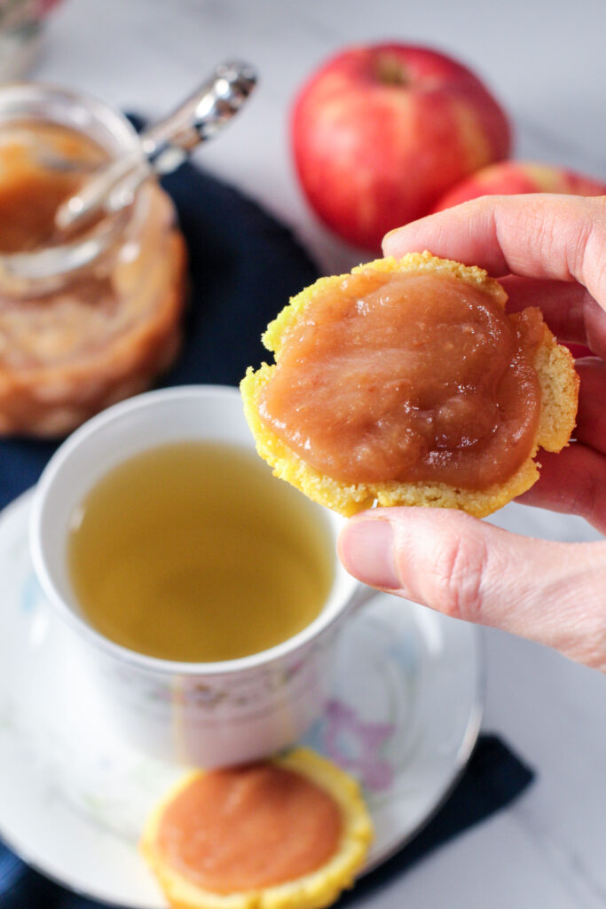 hand holding biscuit topped with apple butter