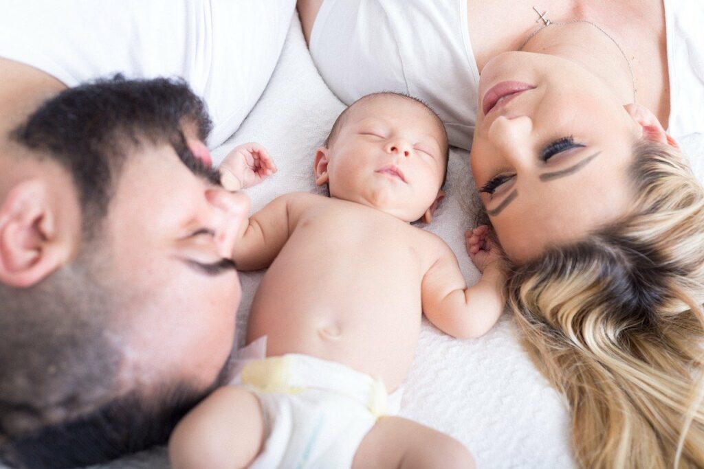 mom and dad laying with baby in diaper