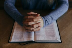 hands folded in prayer on Bible