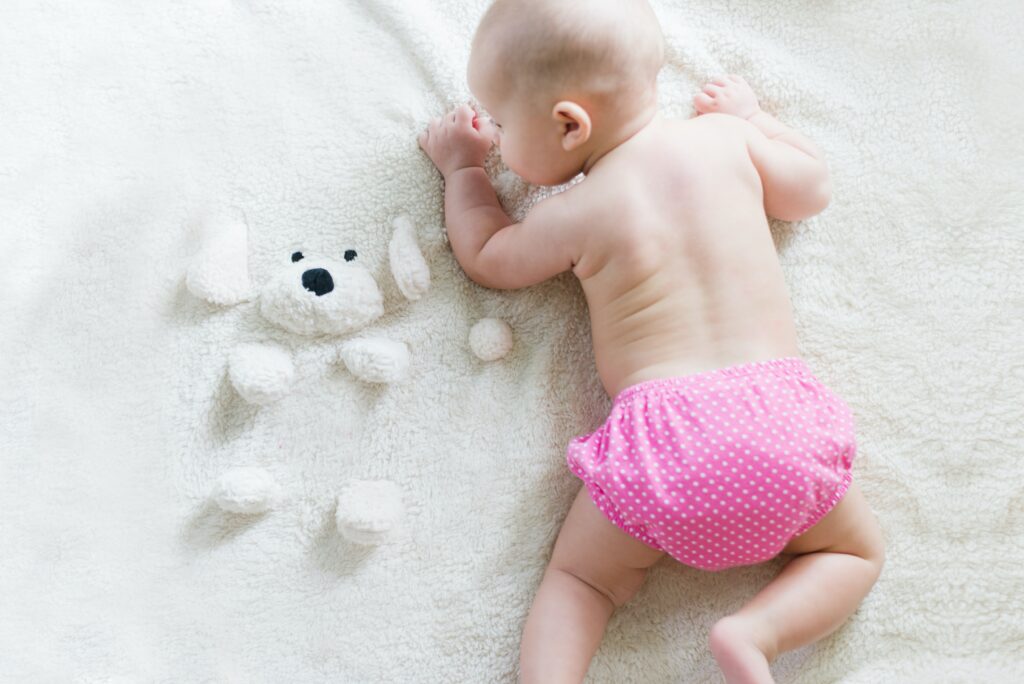 baby in cloth diaper laying on soft white blanket