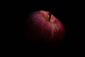 black background with red apple half showing