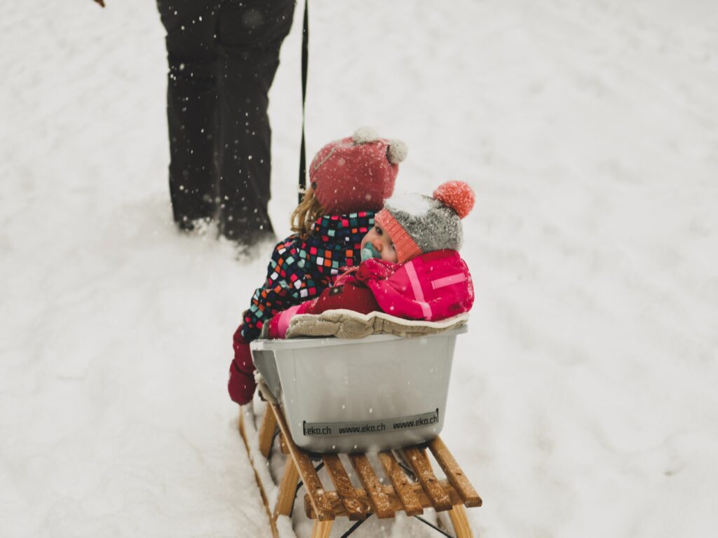 kids riding in sled with someone pulling them up the hill