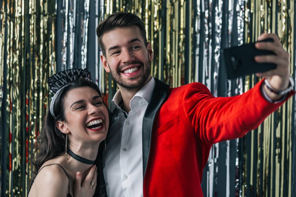 couple taking a new years eve selfie in a home made photo booth