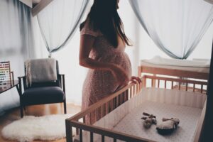 pregnant woman looking down at crib