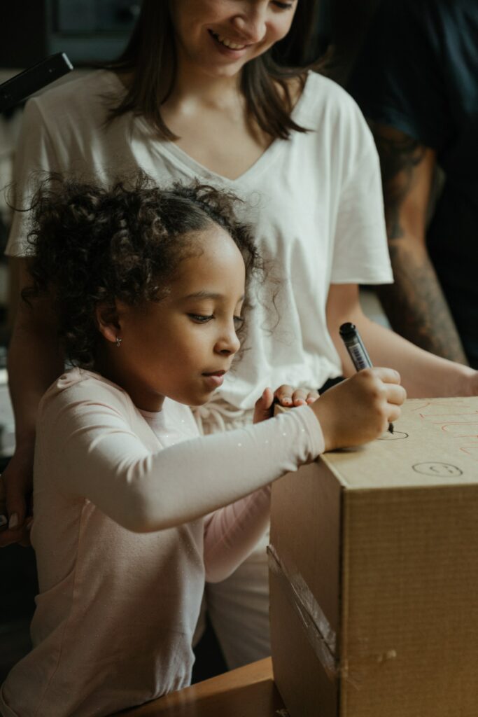 little girl writing on box