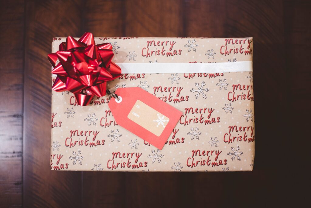 gift wrapped in Merry Christmas paper with red bow and tag