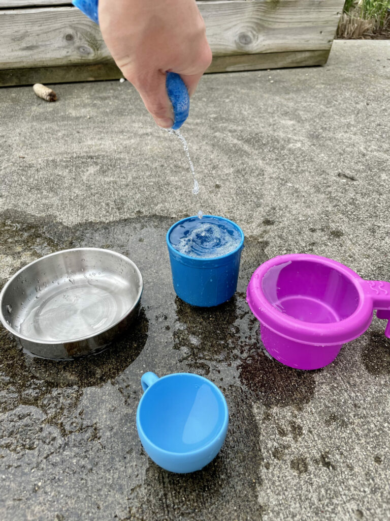 hand squeezing water into container for easy backyard summer activities