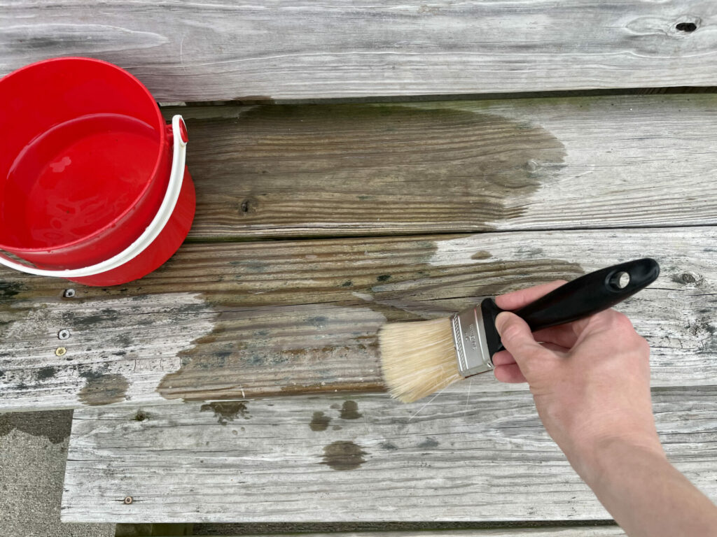 hand using paint brush and water on wood patio for easy backyard summer activities