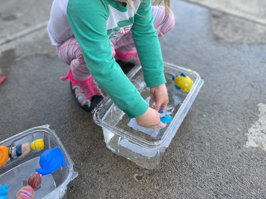 child playing with water toys in plastic bin for easy backyard water activities