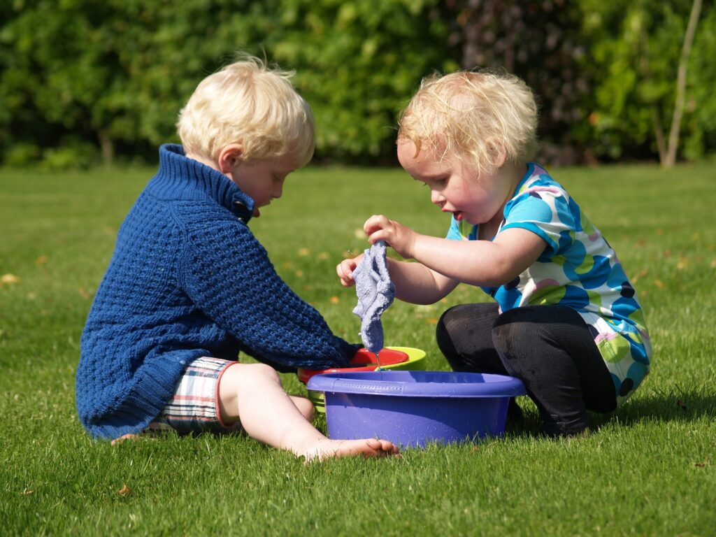 two kids playing with wash cloth and buckets of water