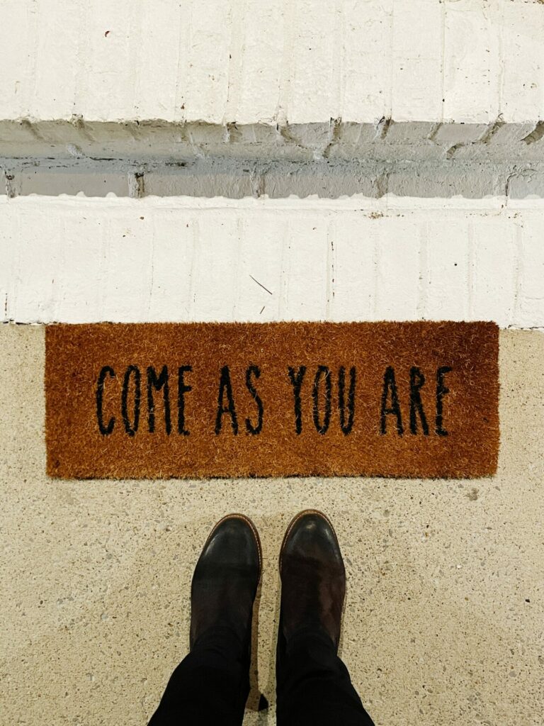 black shows standing by rug that says come as you are